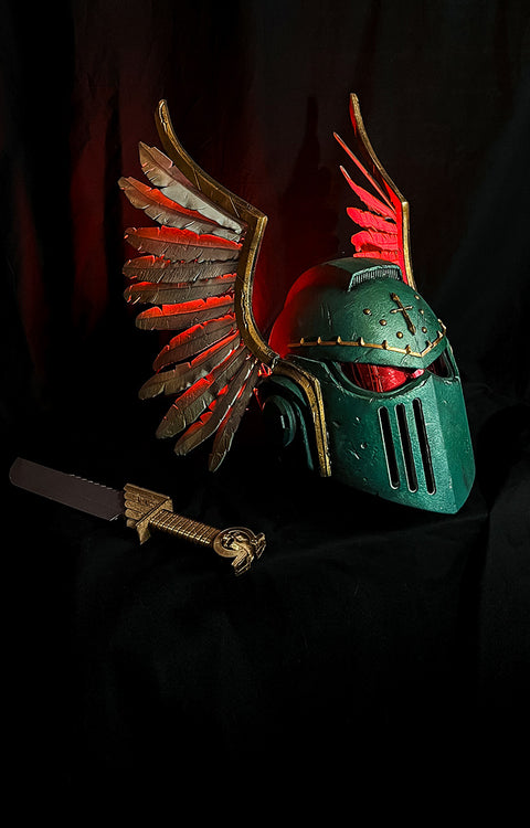 Green decorated 3D printed helmet with Angels wings and a sword on a dark background