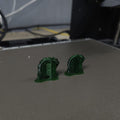 Photo of two freshly 3D printed Slay the Spire green Snake Rings on Prusa 3D printer bed with support structures still attached