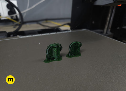 Photo of two freshly 3D printed Slay the Spire green Snake Rings on Prusa 3D printer bed with support structures still attached