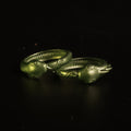 Lifestyle photo of two 3D printed Slay the Spire Snake Rings metallic green alternate angle on black surface showing head and tail detail