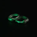 Lifestyle photo of two 3D printed Slay the Spire Snake Rings in metallic green on black surface showing snake head with red eyes silver body detail