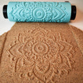 Close-up photo of turquoise 3D printed dense repeating floral mandala pattern roller next to its crisp imprint in brown clay showing intricate linework