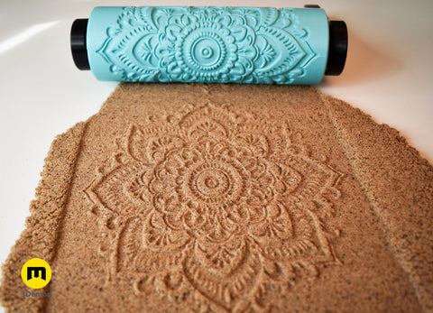 Close-up photo of turquoise 3D printed dense repeating floral mandala pattern roller next to its crisp imprint in brown clay showing intricate linework