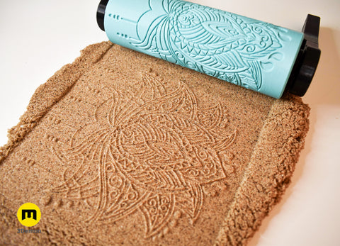 Close-up photo of turquoise 3D printed multi-layered complex mandala roller with deep precise imprint in brown sand showing high detail output