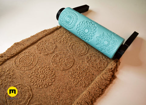 Photo of turquoise 3D printed repeating floral petal mandala pattern roller next to its clear imprint in brown clay showing petal arrangement detail