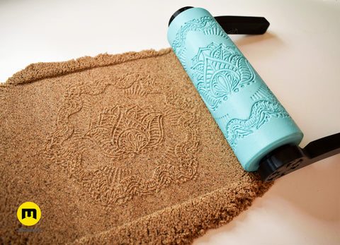 Photo of turquoise 3D printed complex geometric concentric circles and triangles mandala roller alongside deep precision imprint in brown clay