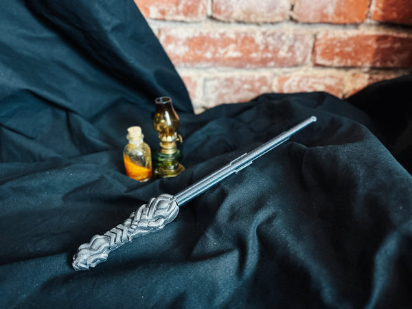 Disassembled 3D printed magic wand parts with a metallic silver finish resting on black fabric.
