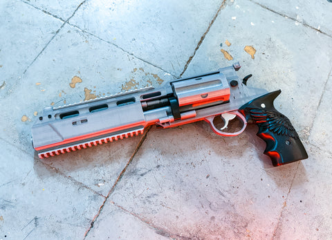 Decorative revolver gun with red light, silver and black accents on a concrete surface. Resident Evil Leon's prop 3D printed file by 3Demon.