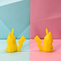 Yellow 3D printed Pikachu figurines on a pastel pink and blue geometric background. One is a girl, one is a boy.