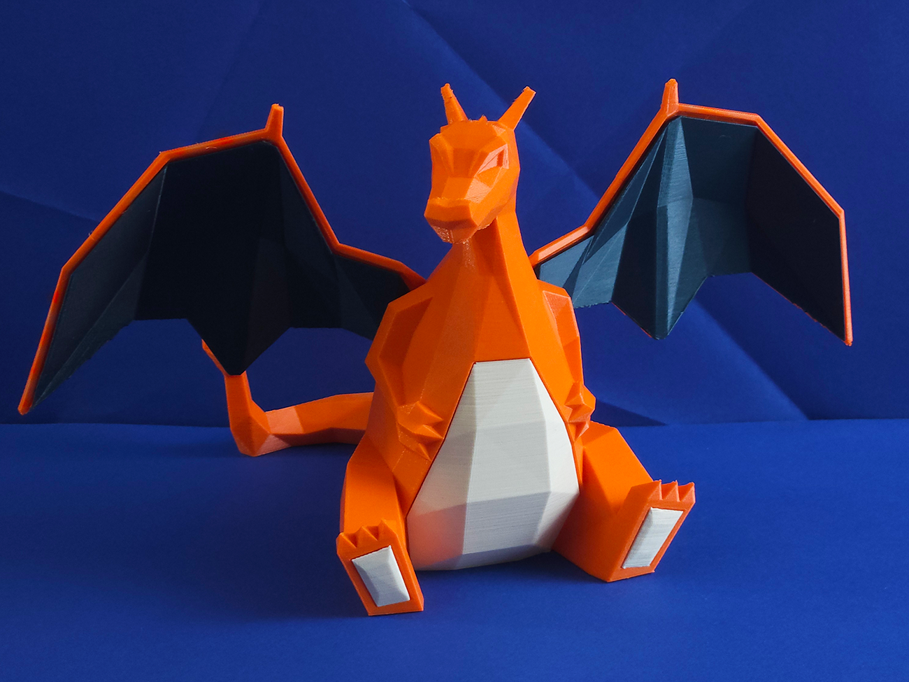 Photo of 3D printed Charizard STL collectible figure, orange/white, seated front view.