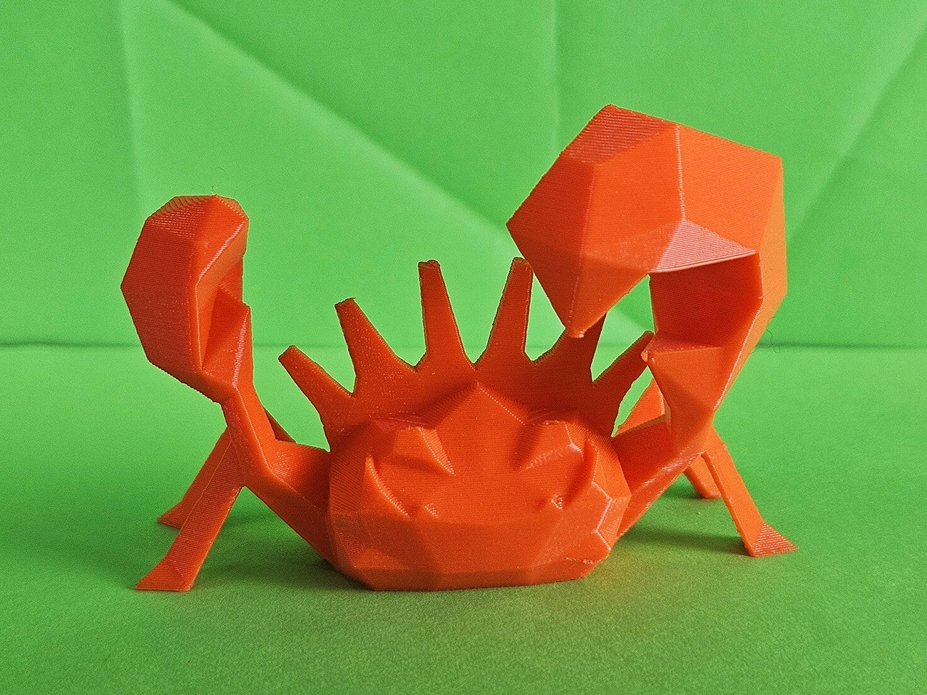 3D printed Kingler STL collectible figure, orange, dynamic side pose, plain green background