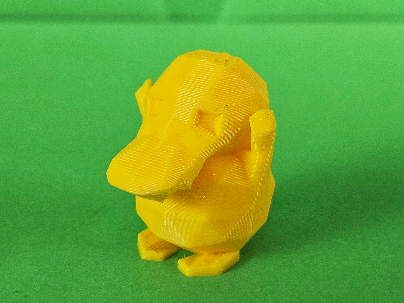 3D printed Psyduck STL collectible figure, yellow, side profile view, plain green background