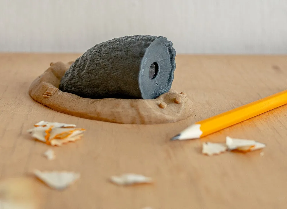 Lifestyle photo of Sandworm Pencil Sharpener - Dune, 3D printed clay model with pencil shavings.