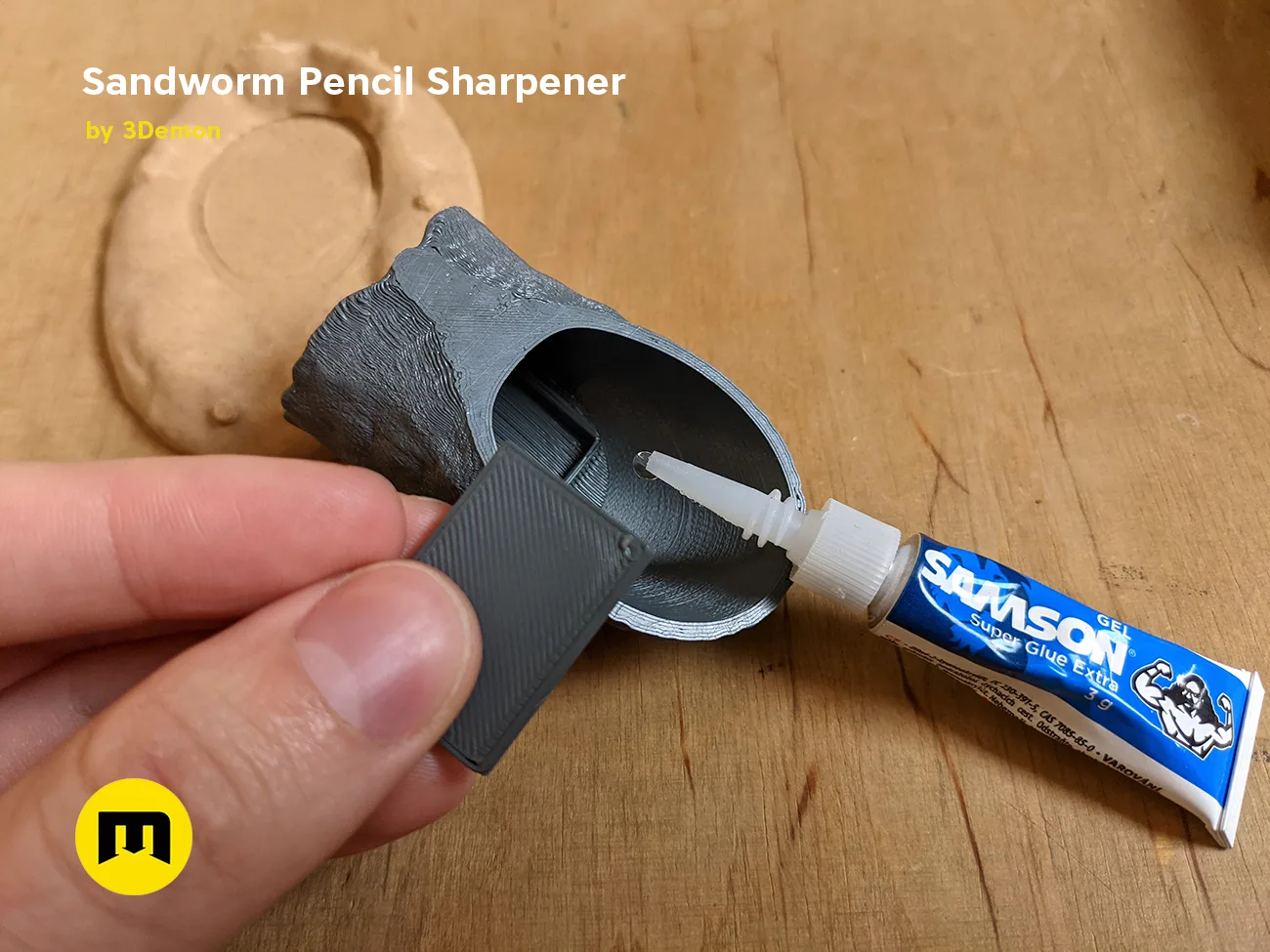 Hand photo of Sandworm Pencil Sharpener 3D print, Dune-inspired design with glue application detail.