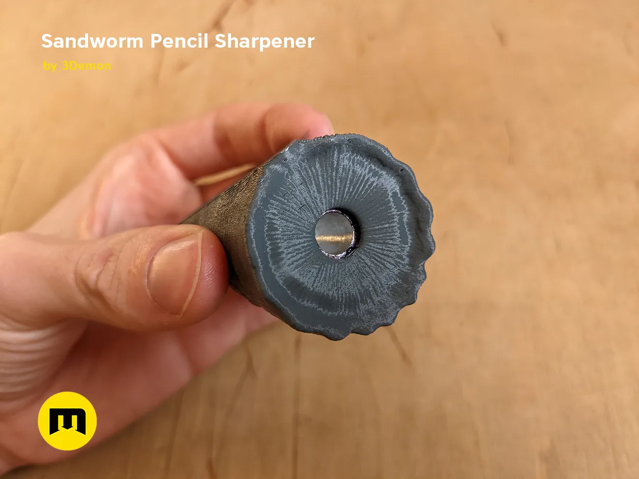 Hand photo of Sandworm Pencil Sharpener - Dune 3D print, black textured top with central hole.