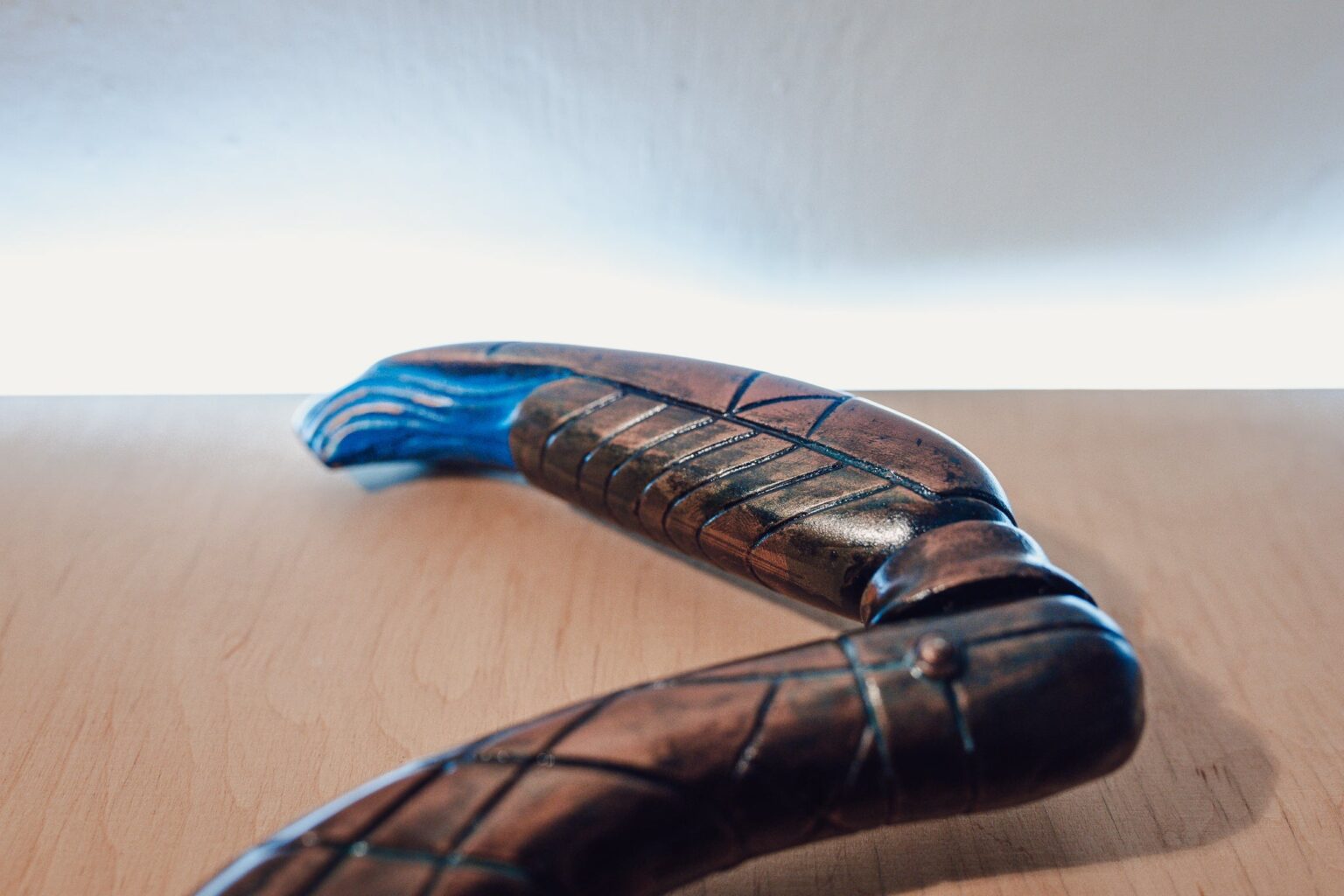 Lifestyle photo of Zat'nik'tel Gun 3D printed prop, wooden-textured sci-fi firearm on table