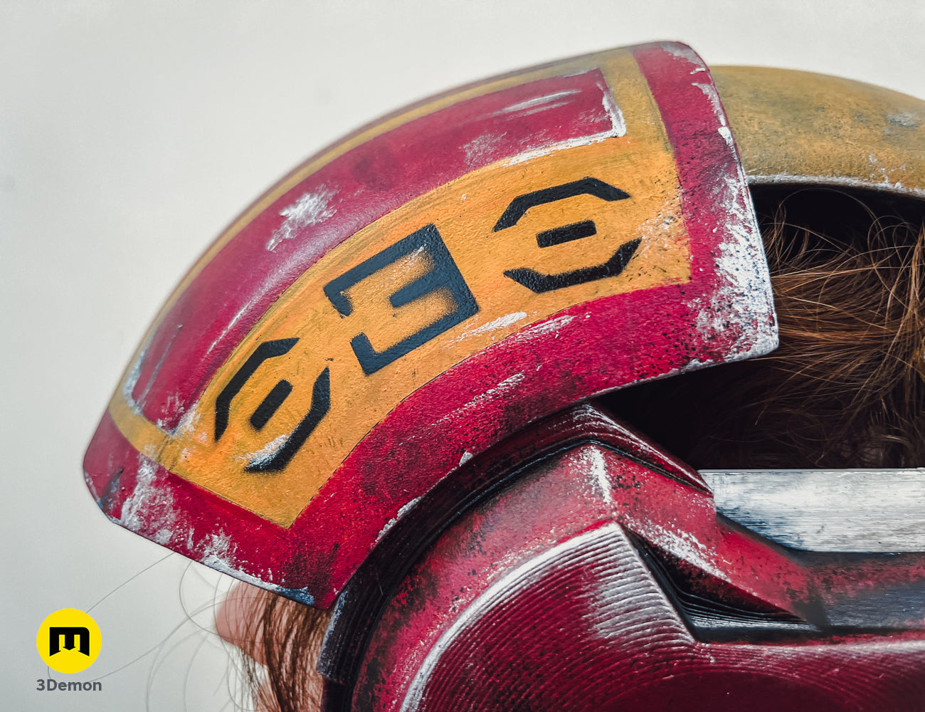 Close-up of Sabine Speeder Helmet - Ahsoka, red and gold 3D printed cosplay prop with weathered details