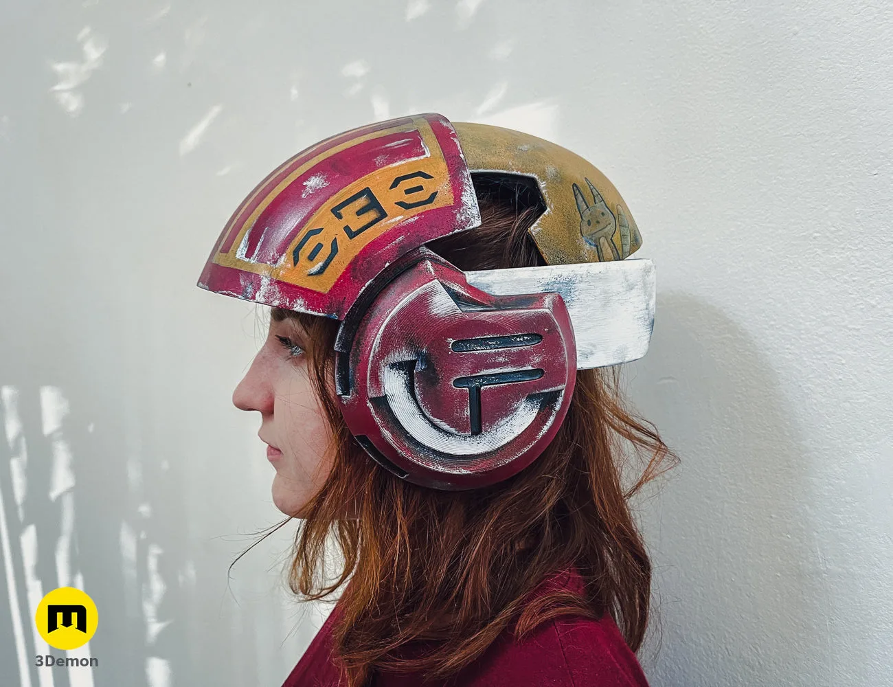 Lifestyle photo of 3D printed Sabine Speeder Helmet - Ahsoka cosplay prop, maroon and gold, multi-part design.