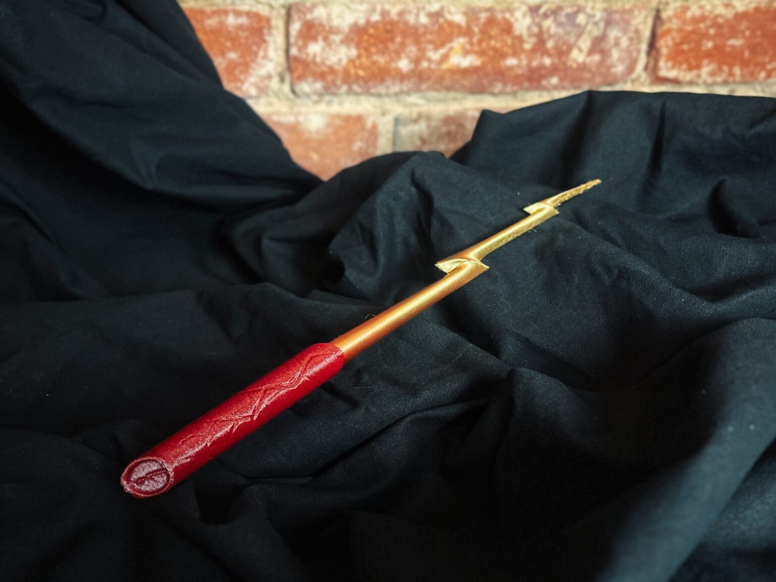 Real photo of a 3D printed Flash magic wand with a red lightning handle and golden lightning tip cosplay prop.