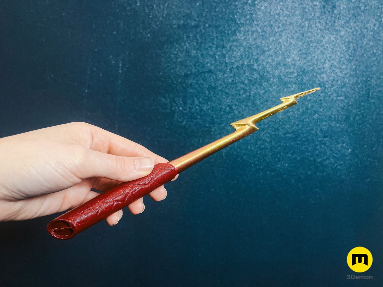 Hand holding a 3D printed Flash magic wand with a red handle and golden lightning bolt tip cosplay prop.
