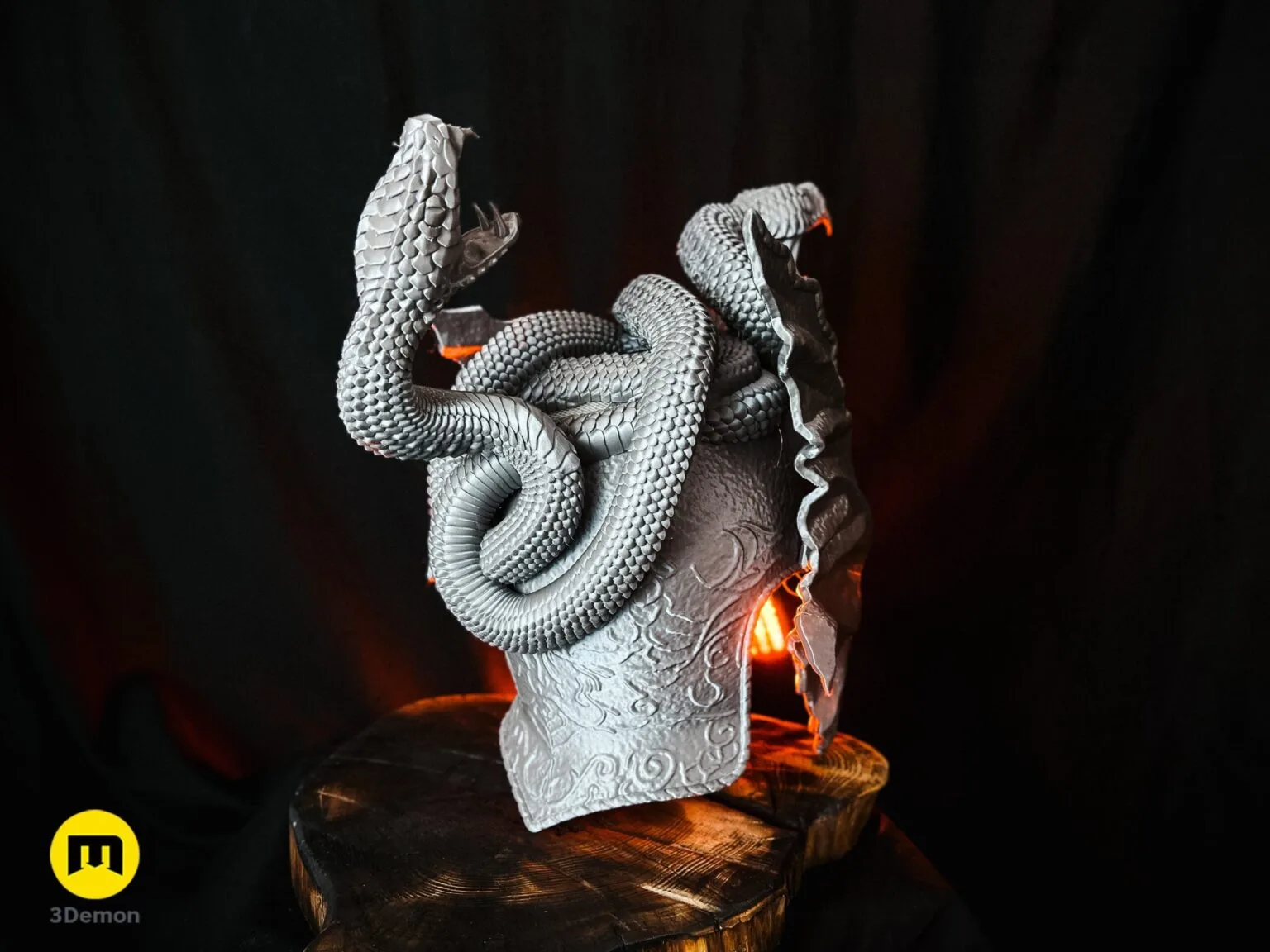 Lifestyle photo of a grey 3D printed Messmer helmet featuring large detailed snake figures on the crown.