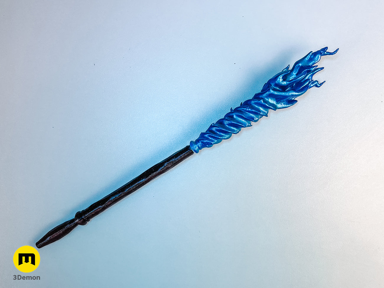 Real photo of an assembled 3D printed magic wand with a black handle and white flame topper on a white surface.