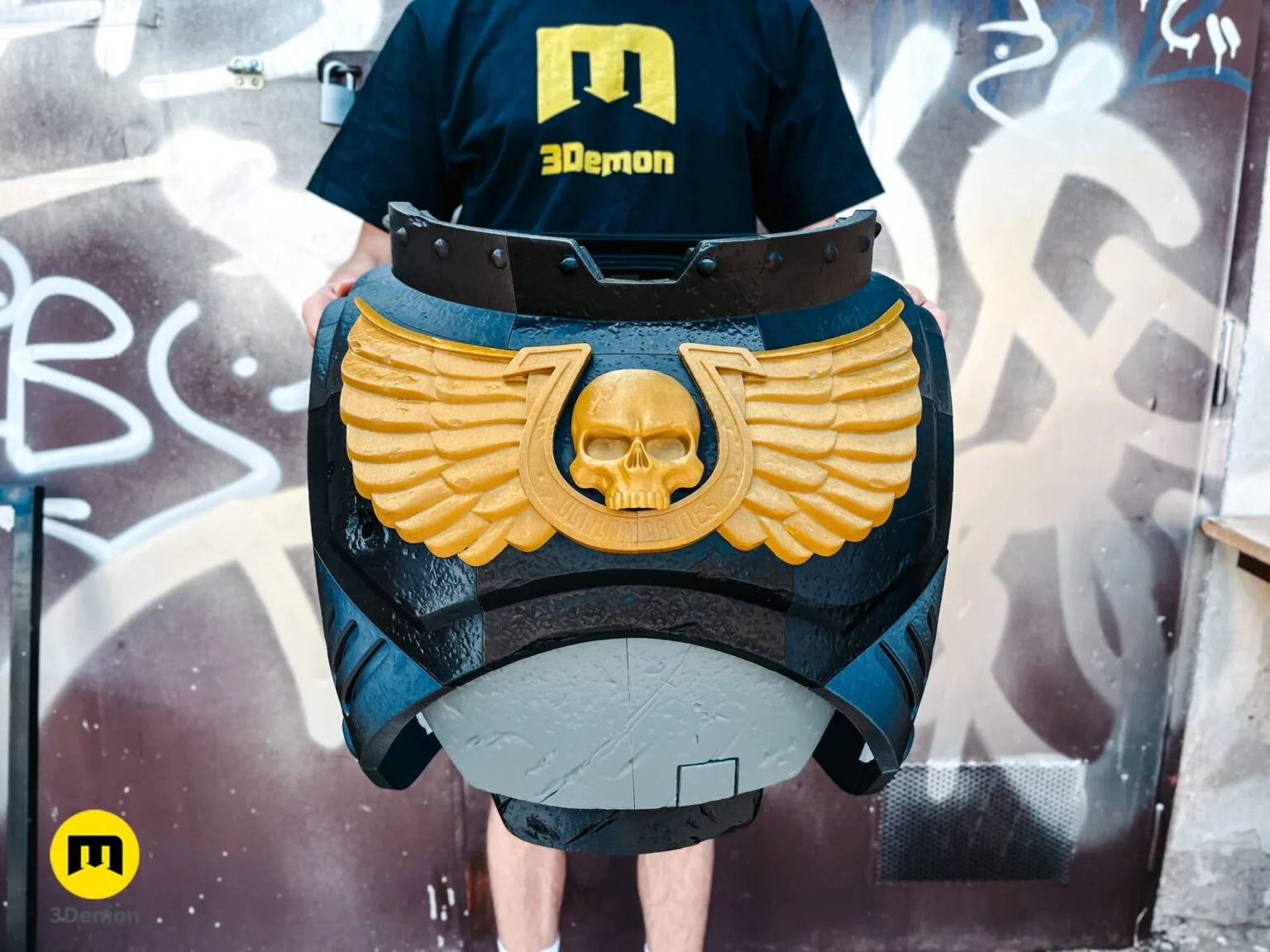 A person wearing the full 3D printed black and grey Space Marine chest and abdomen armor with a golden Aquila.