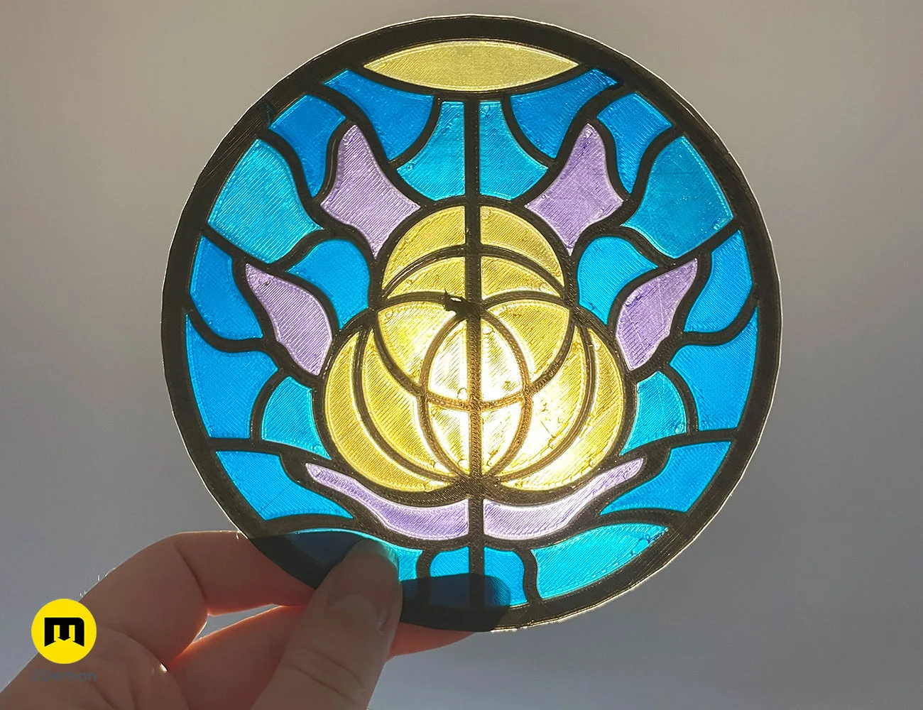 Hand-held 3D printed Elden Ring logo stained glass panel, backlit showing blue and yellow colors – Elden Ring Stained Glass 3D print | 3Demon