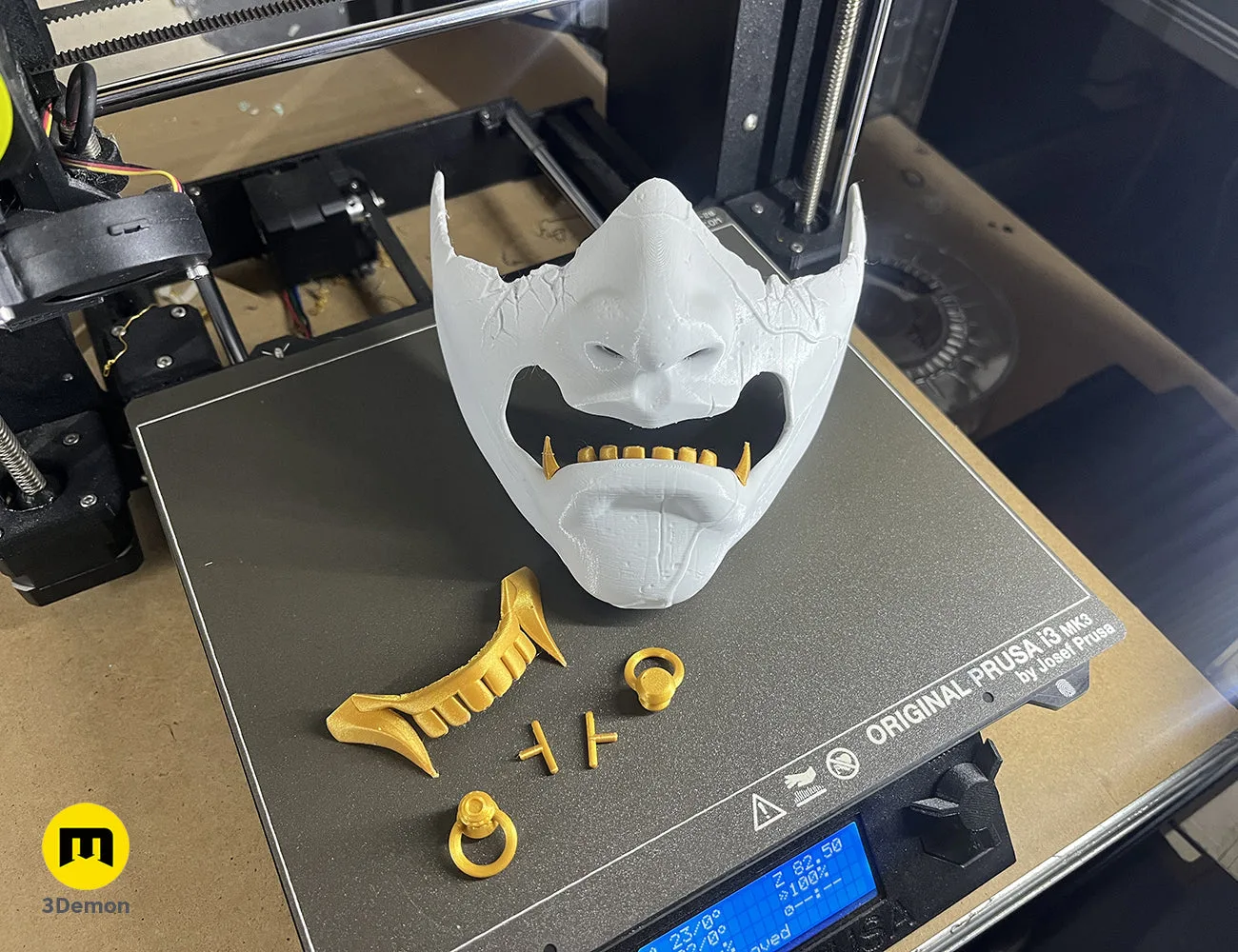 Hand-painted white samurai mask with gold teeth and weathered cracks, held against black background – Ghost of Yotei Samurai Mask 3D print | 3Demon