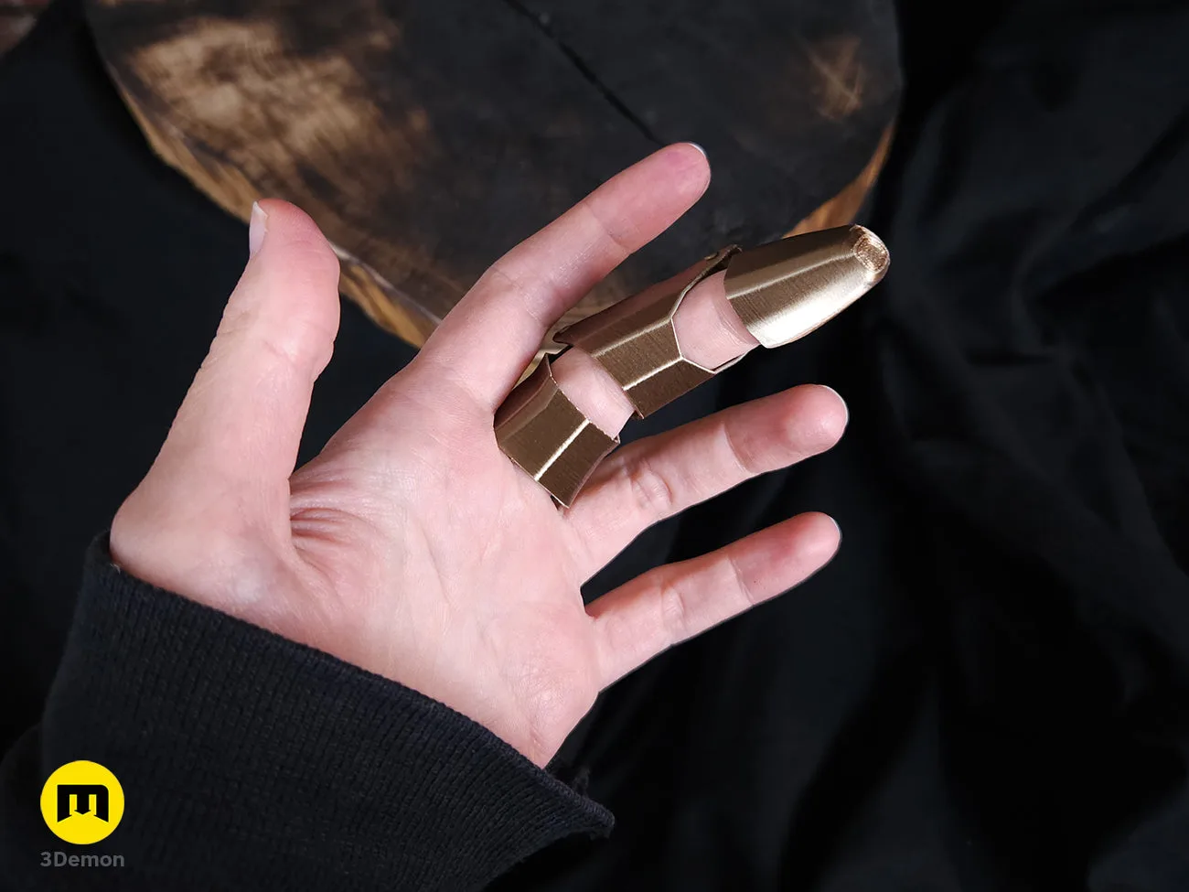Single bronze 3D printed Jinx finger armor piece on a black surface – Jinx Finger from Arcane 3D print | 3Demon