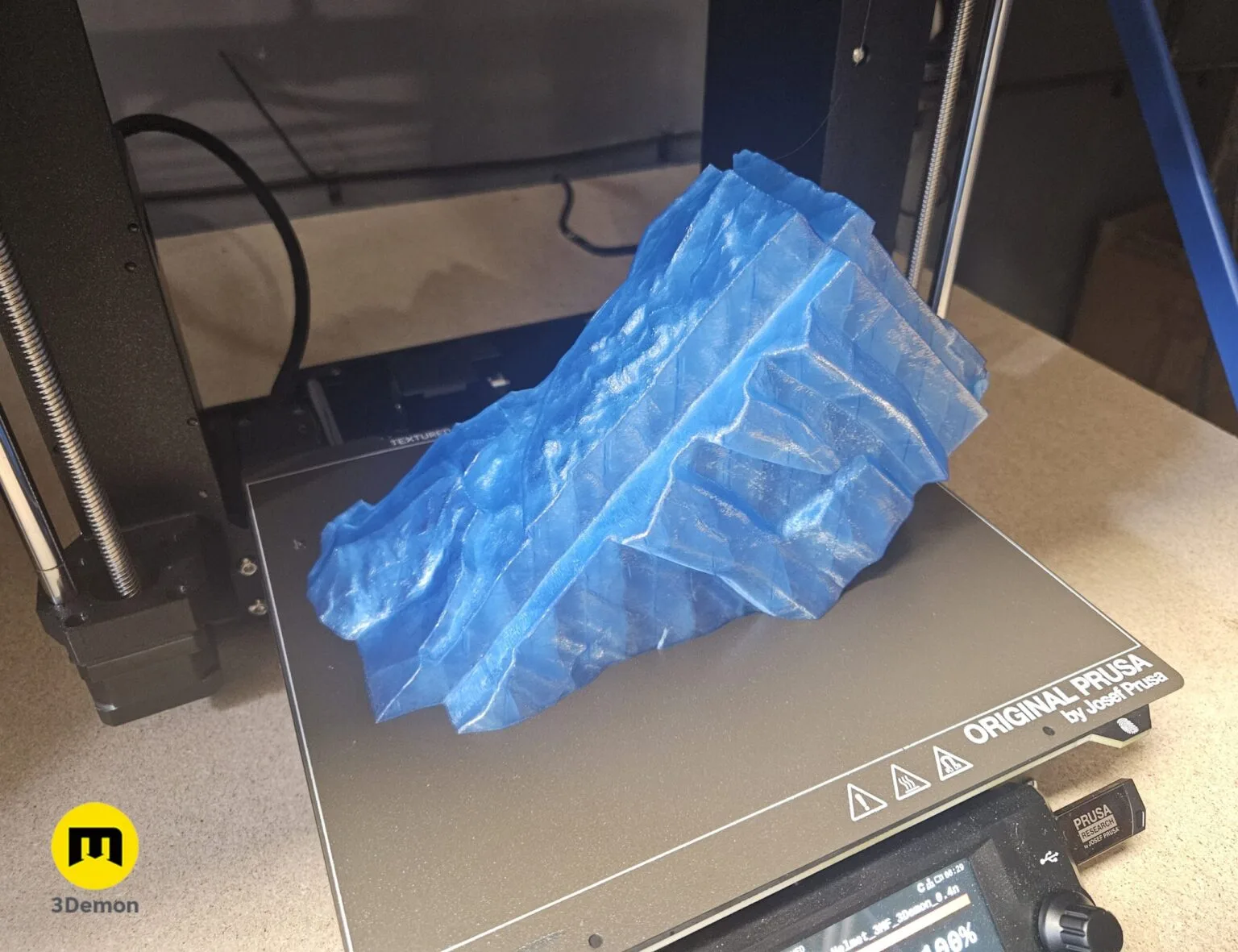 Lifestyle photo of individual 3D printed translucent blue PLA Crystal Clear segments of Minecraft Movie helmet laid out on table showing cubic block pieces before assembly