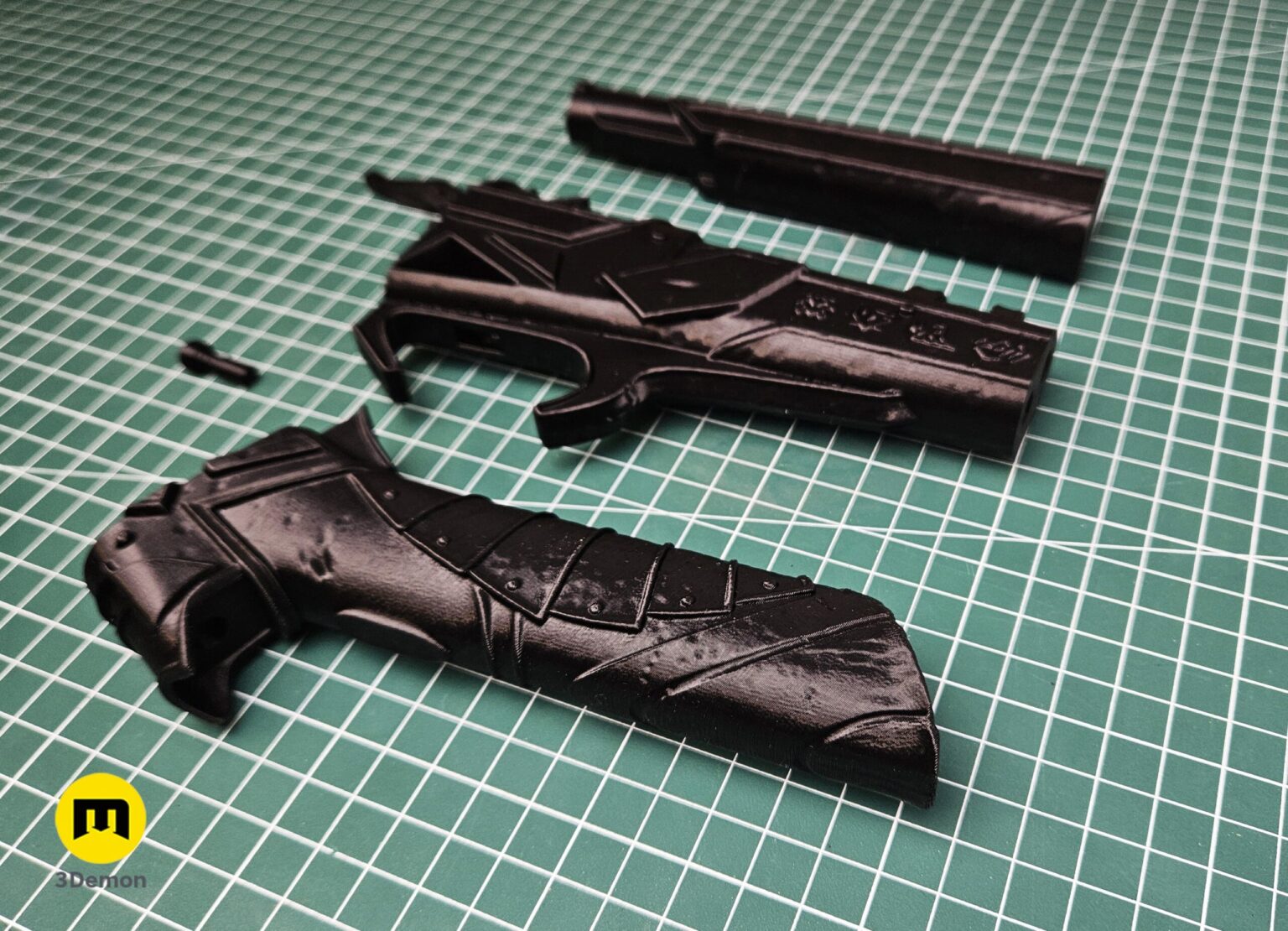 Photo of individual Expedition 33 Gustave Gun 3D printed components laid out on dark surface showing all raw grey parts before assembly