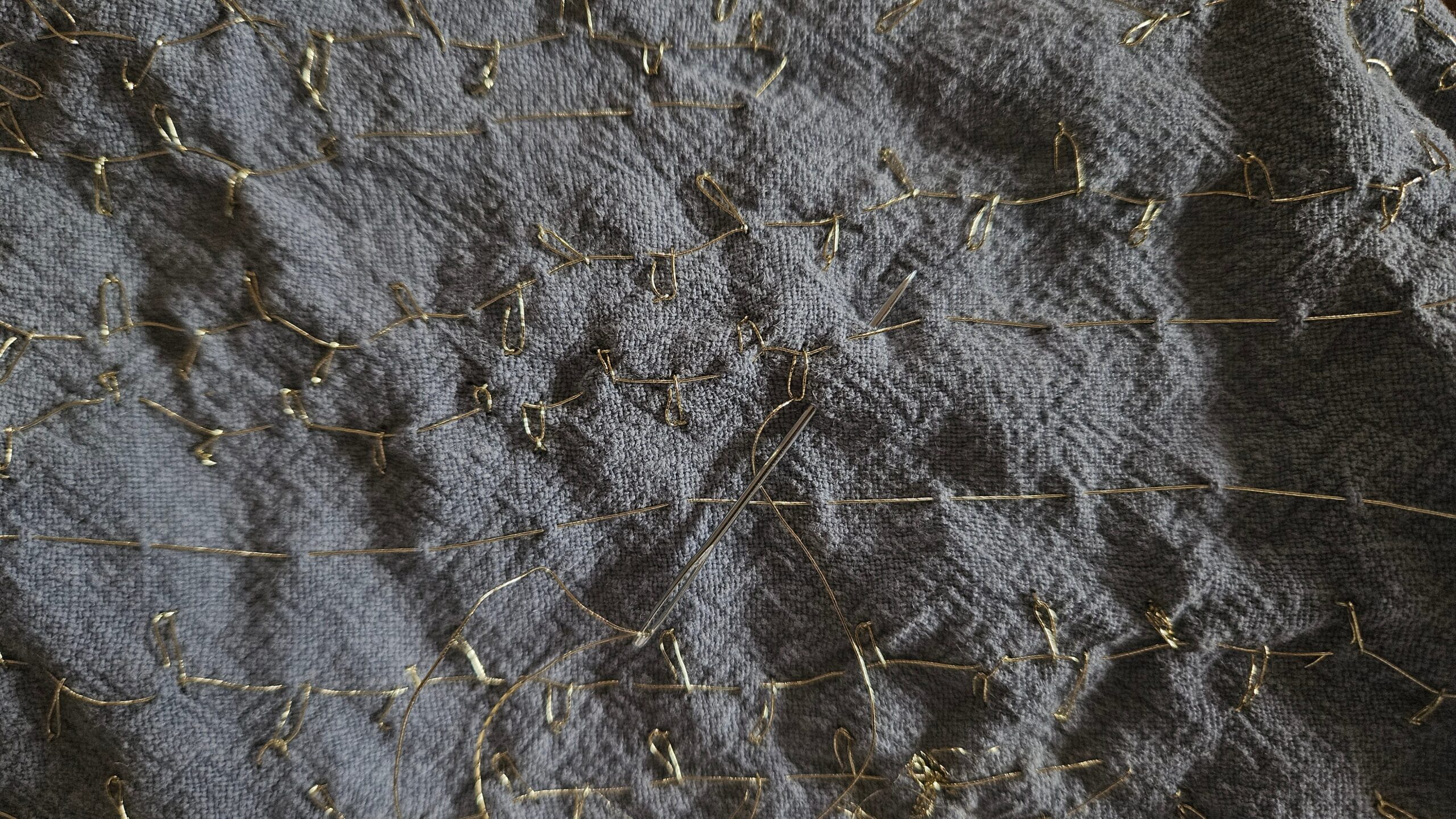 Hand-sewn gold detail stitching across the blue fabric