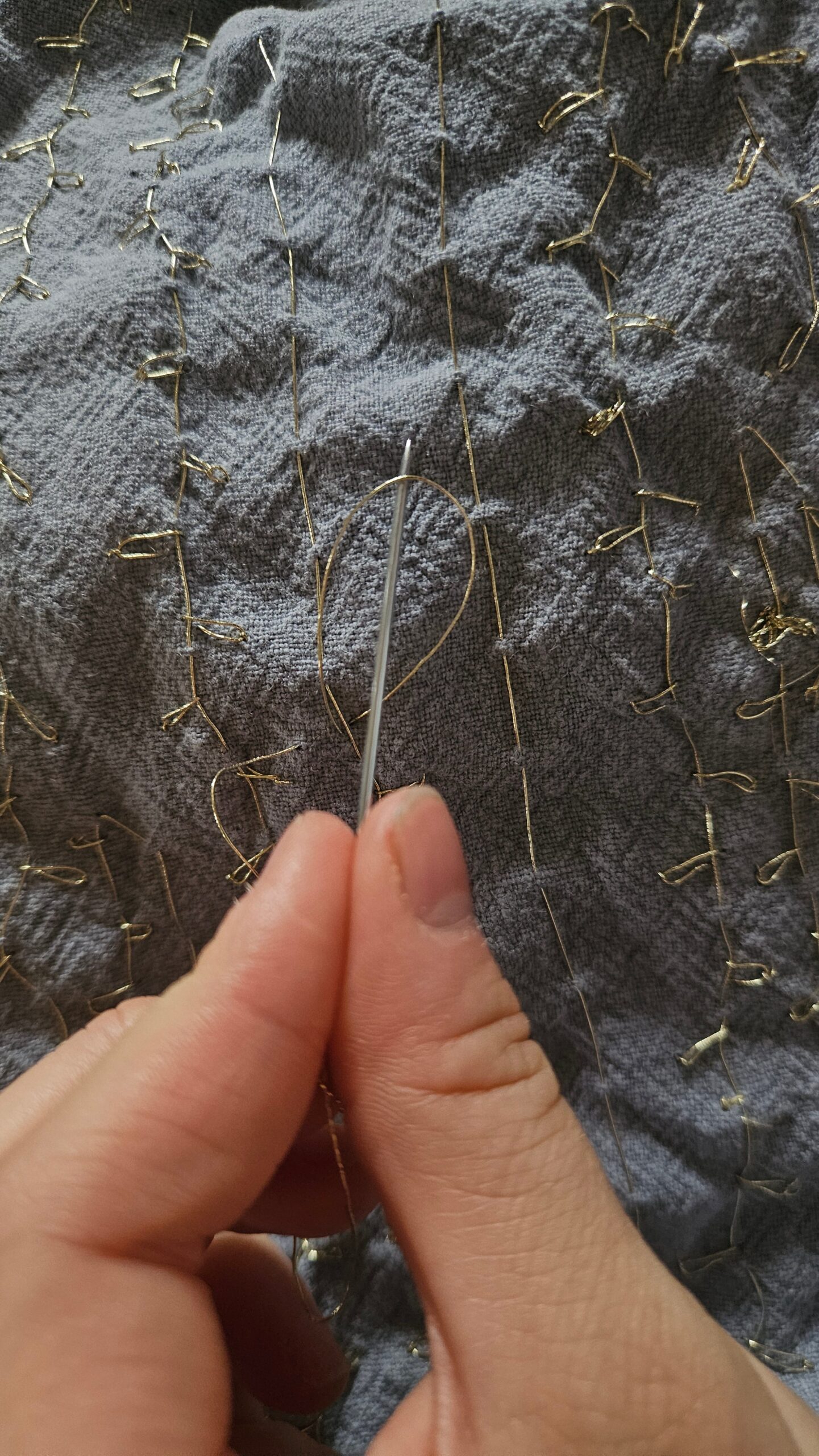 Hand-sewing the gold embroidery detail with a needle