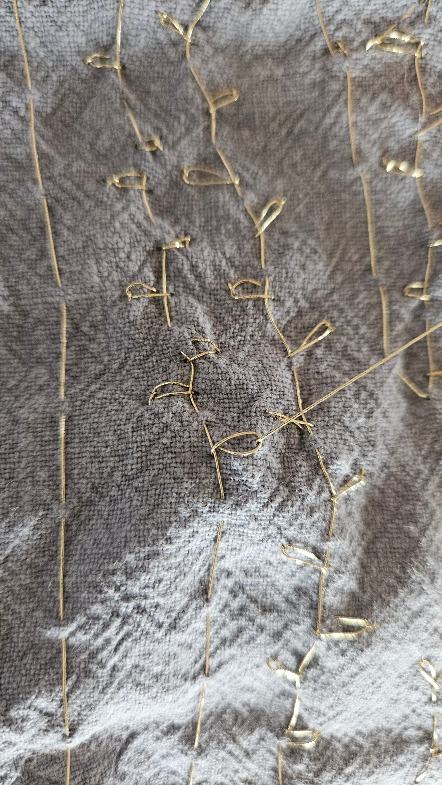 Gold embroidery pattern building up across the fabric