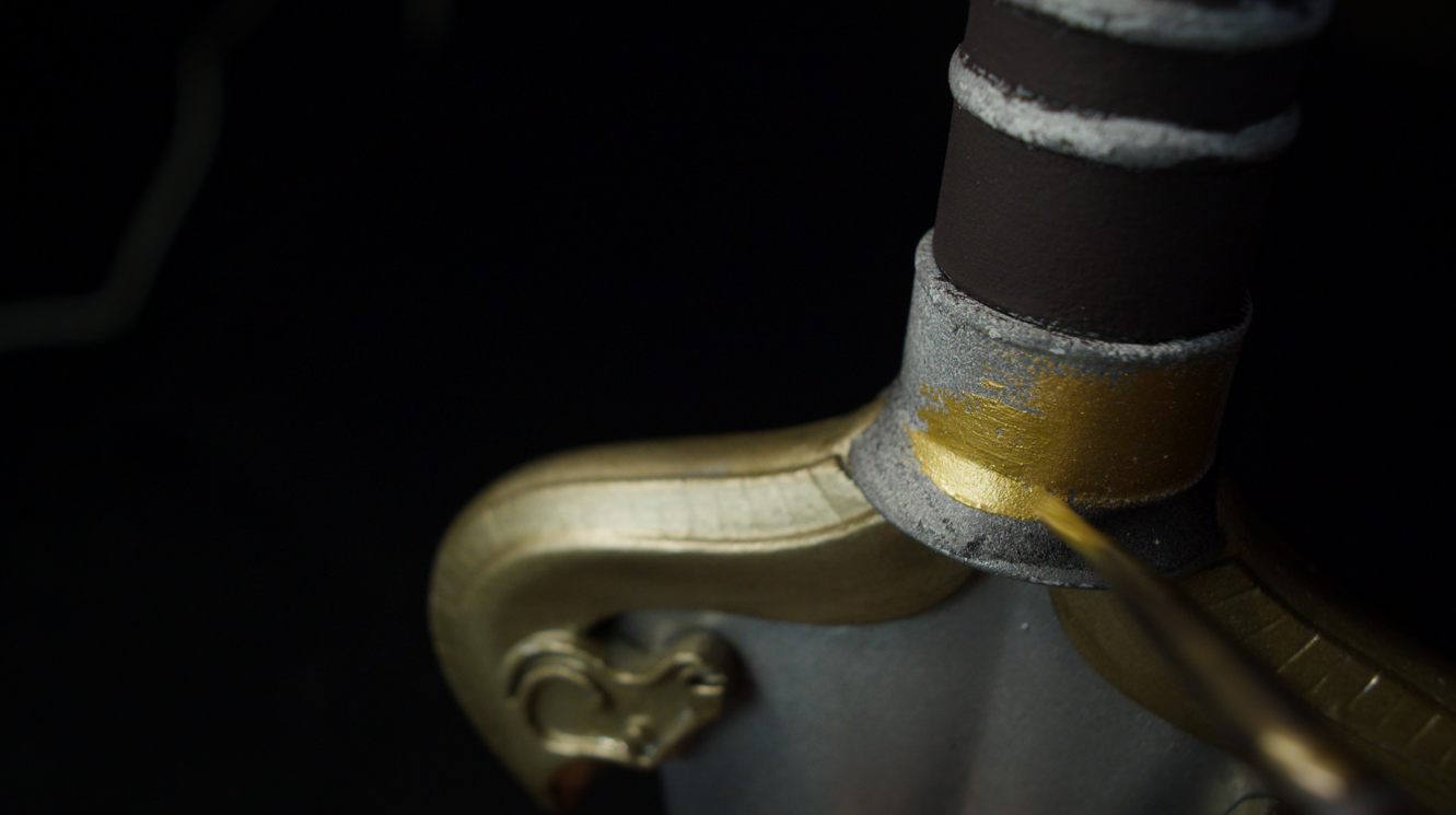 Gold-painted crossguard photographed on a dark background