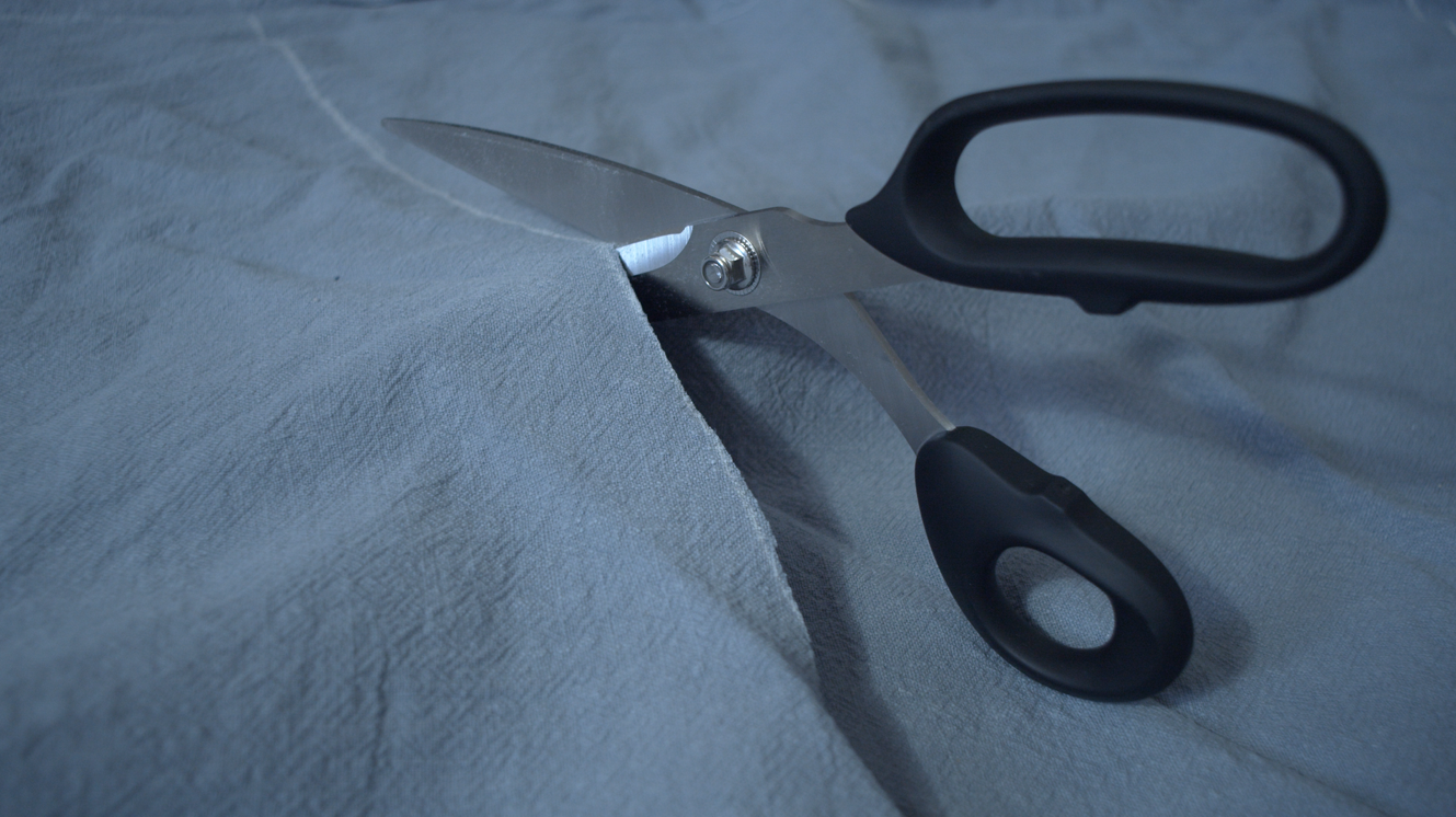 Cutting the blue linen along the traced pattern lines