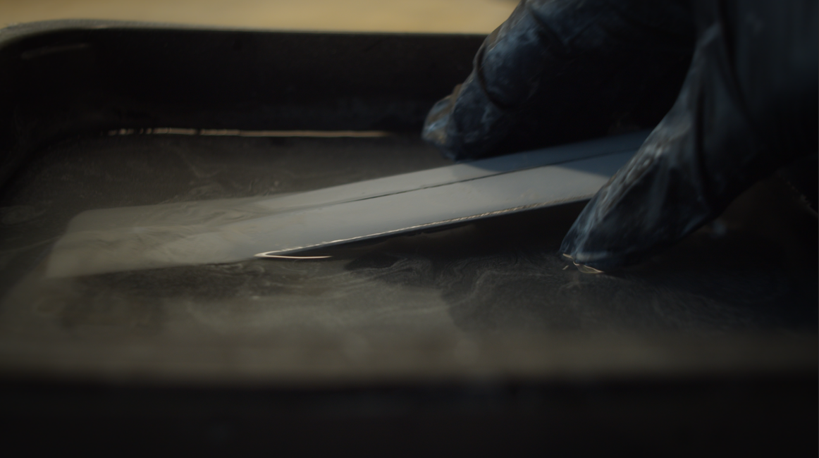 Wet sanding the primed sword blade in a tray of water