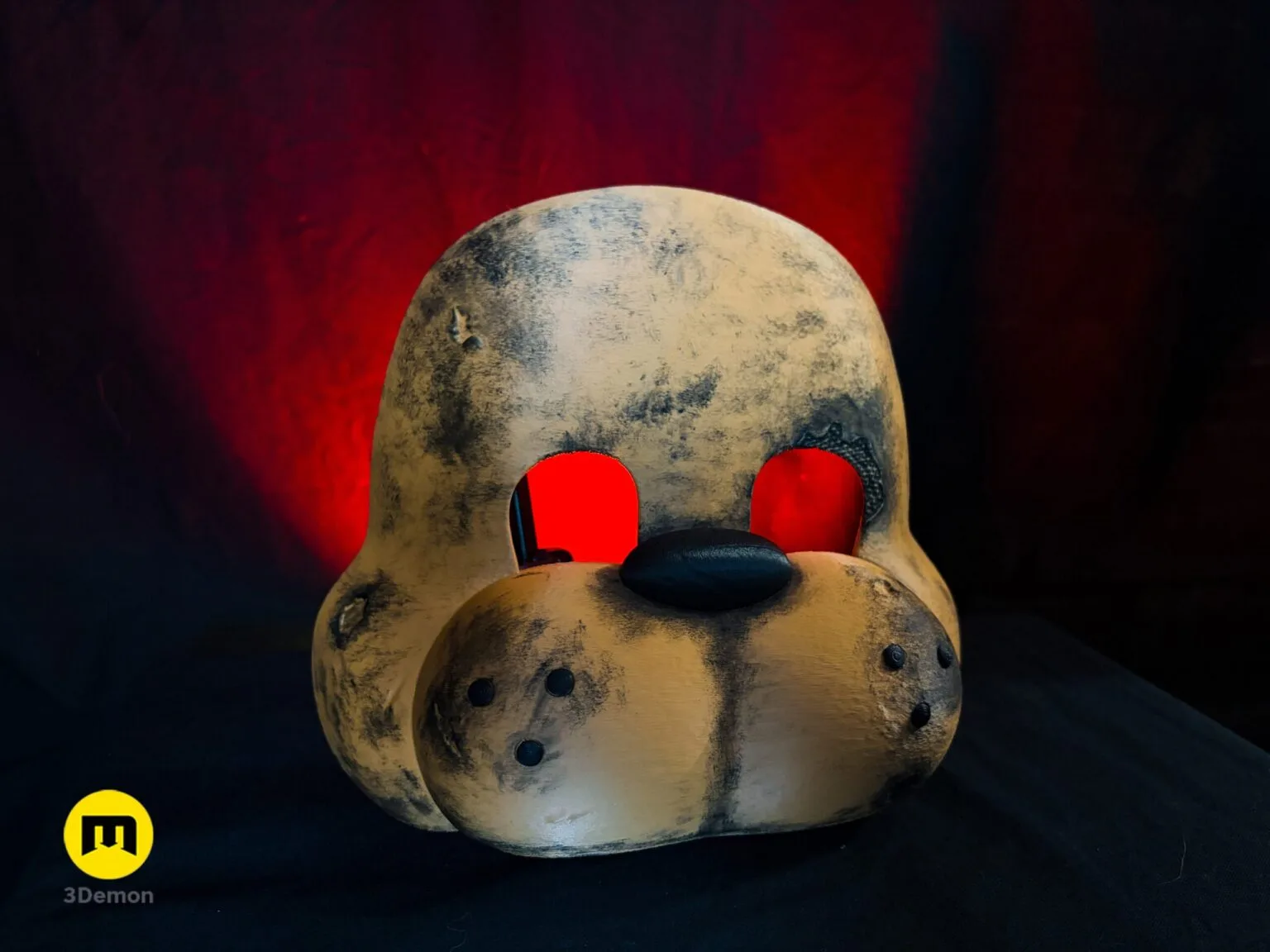 Angled top-down photo of weathered Freddy Fazbear mask showing forehead texture round bear ears built-in rubber strap loops and glowing red eye sockets