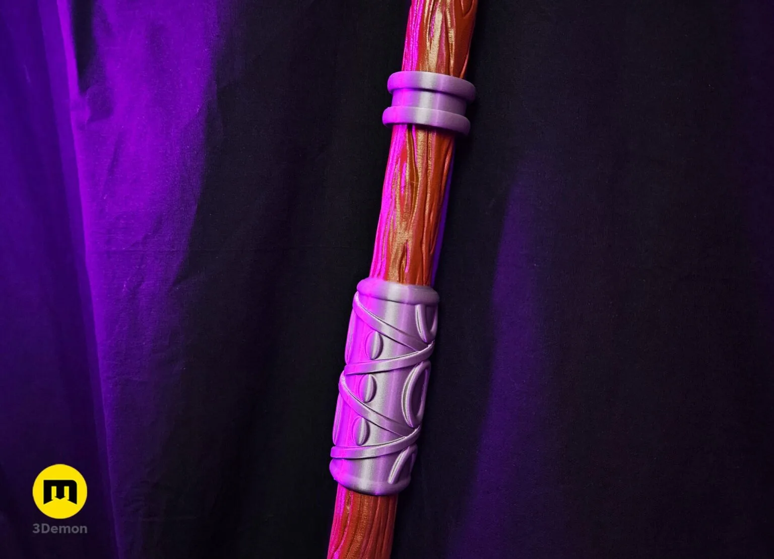 Close-up lifestyle photo of Fern Staff Frieren head resting on black surface showing realistic wood grain paint job and metallic sheen of silver accent rings on upper shaft