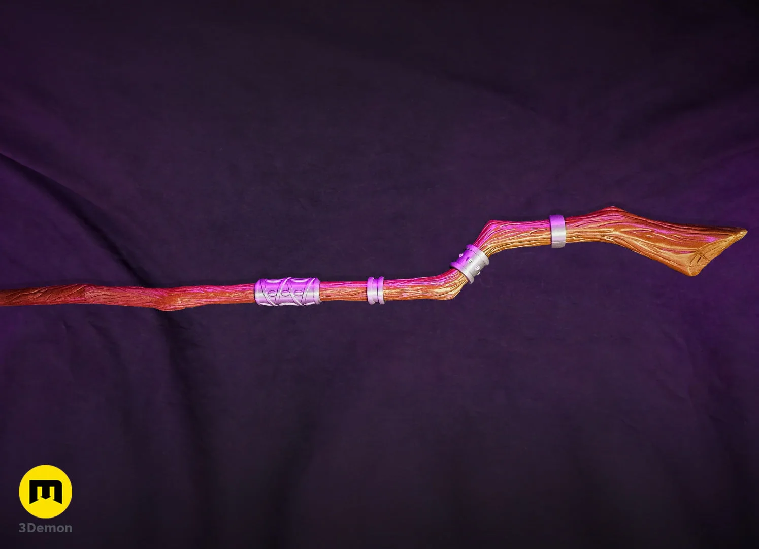 Lifestyle photo of complete assembled Fern Staff Frieren lying horizontal showing full length contrast between white pearlescent head and tan wood-grain painted long shaft with silver rings